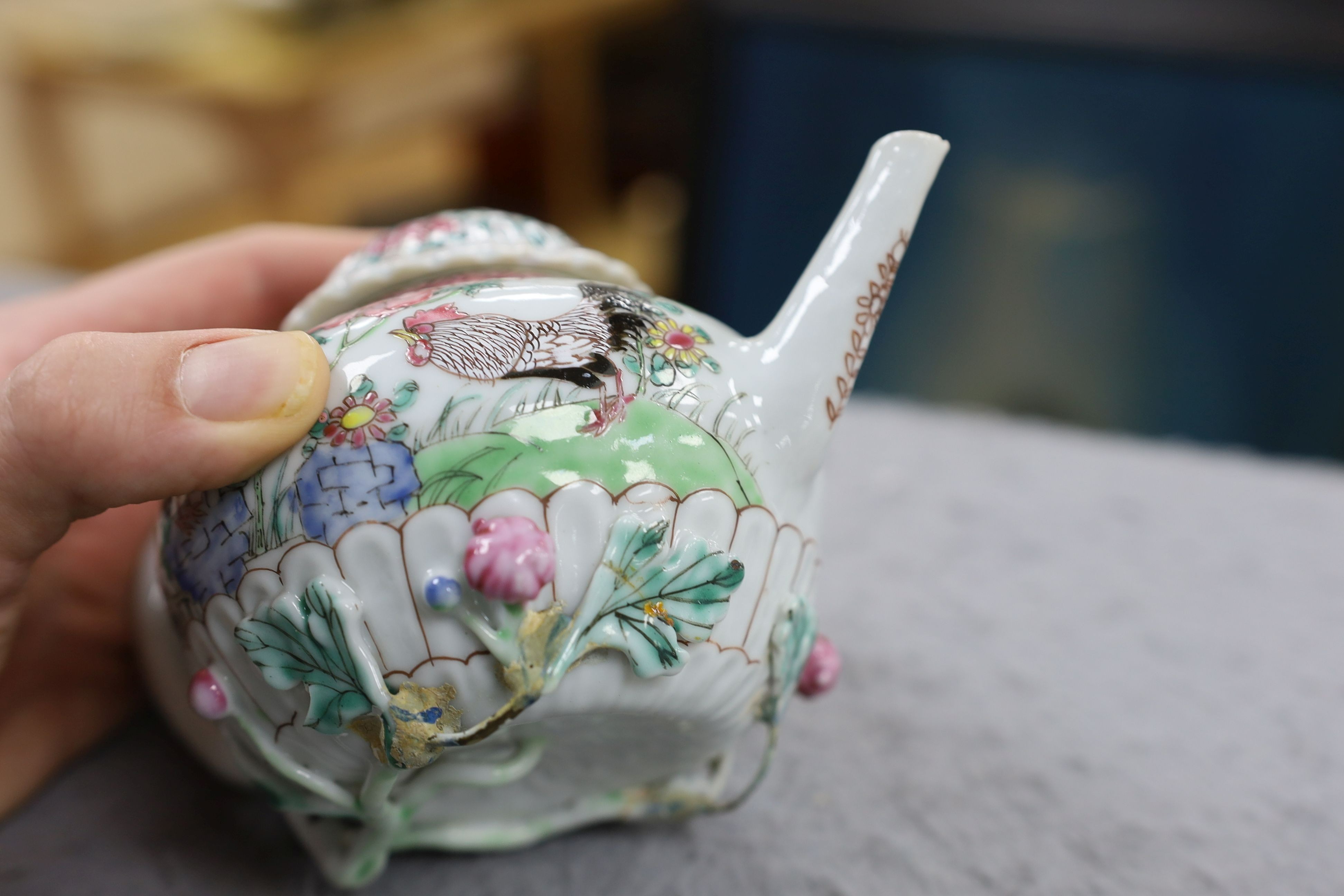 A Chinese famille rose chrysanthemum moulded teapot, early Qianlong period, painted with a cockerel amongst flowers, on a cage work base, 10 cms high